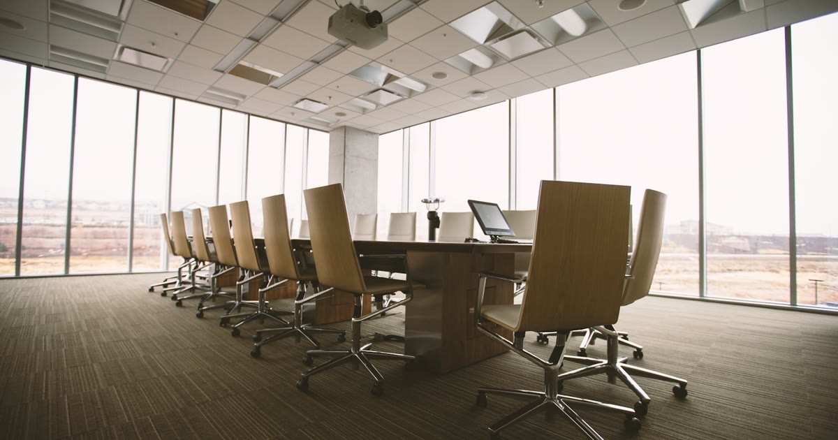 Empty conference room with chairs around a table and one unused laptop